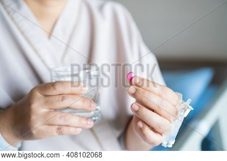 Patient Eating Medication To Treat Disease, Holding Pill Tablet And Glass Of Water In Hands For Taki