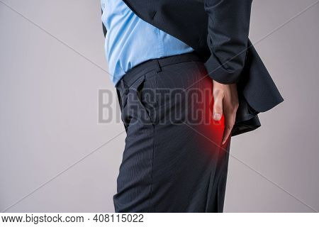 Office Worker Suffering From Hemorrhoids, Anal Pain On Gray Background