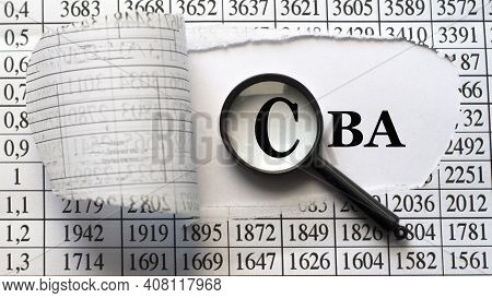Cba (cost Benefit Analysis) - Word Behind Torn Paper With Numbers On A White Background With A Magni