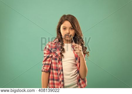 Serious Kid With Funny Party Moustache. School Girl Ready For Fun. Happy Childhood. Child Try To Mak