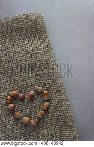 Nuts Laid Out In The Shape Of A Heart On Burlap With Nuts With Gray Background. Organic, Healthy Foo