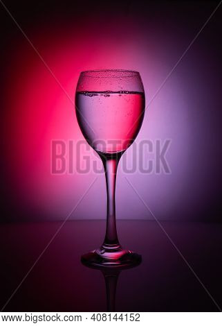 Silhouette Of Transparent Glass Of Whater  On Red And Purple Background