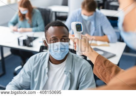 New Normal Rules. Closeup Of Teacher Holding And Looking At Contactless Infrared Themometer Doing Te