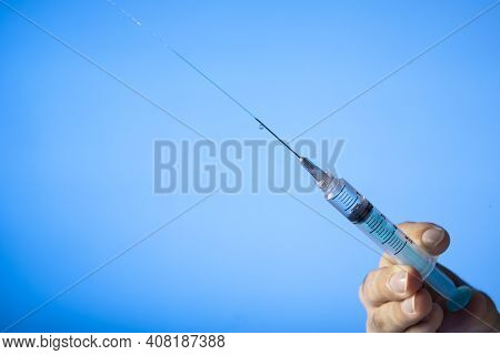 Hand Holding An Syringe With Vaccine. Covid-19 Coronavirus. On Bluebackground
