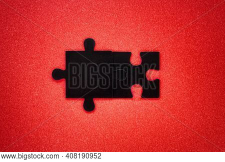 Close-up Of Two Black Pieces Of A Puzzle Put Together On A Red Background