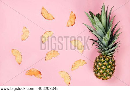 Ripe Juicy Pineapple On Pink Background And Dried Pineapple Wedges Around. Fruit Chips. Healthy Eati