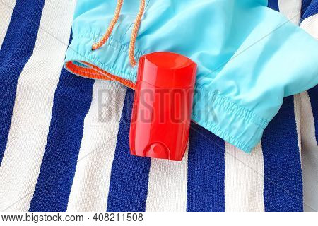 Mockup Of Red Glossy Deodorant Stick, Blank Roll For Deodorant, Striped Towel And Swim Shorts.
