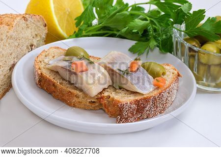 Open Sandwich Made Of Whole Wheat Bread, Slices Of Pickled Atlantic Herring Fillet And Green Olives 