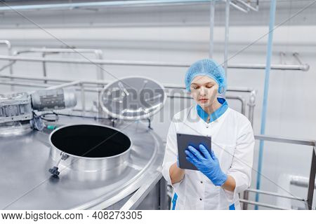 Food Automated Modern Industrial Production. Operator Worker Woman Checks Steel Tanks With Tablet Co