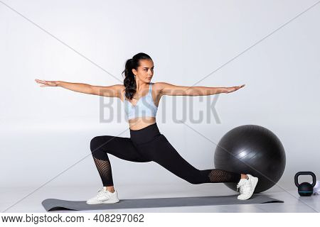 Fit Young Woman In Worrier Yoga Position With Stretched Out Arms And Legs On A Mat. Trainer Showing 