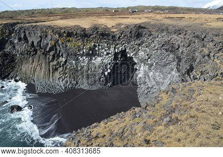 Basalt Columns And Black Sand Beach With Waves Crashing Ashore.