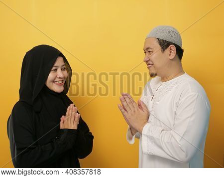 Happy Asian Muslim Couple Doing Greeting Gesture, Apologize And Forgiving Each Other On Eid Mubarak 