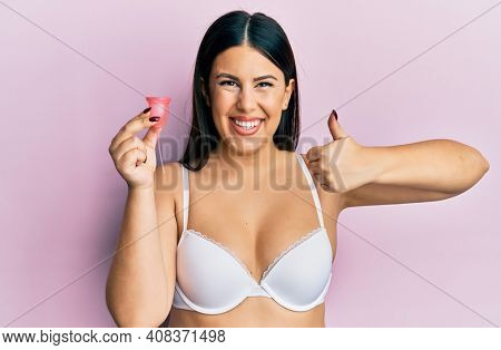 Beautiful brunette woman holding menstrual cup wearing underwear skeptic and nervous, frowning upset because of problem. negative person. 