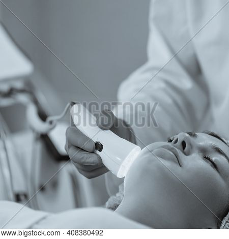 Woman Having Color Light Therapy To Stimulate Facial Skin Wellbeing.black And White Image With Blue 