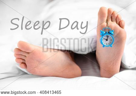 . Sleep Day. A Man Lies In Bed, An Alarm Clock Hangs On His Leg, The Concept Of Laziness, World Slee