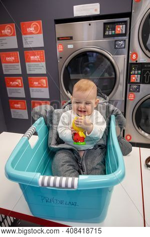 Prague, Czech Republic - 16.12.2020: Baby Girl In The Plastic Basket Waiting In Laundry Room With Sp
