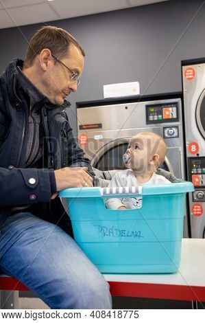 Prague, Czech Republic - 16.12.2020: Man With His Baby Waiting For Laundry In Laundry Room With Spee