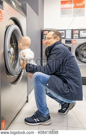 Prague, Czech Republic - 16.12.2020: Man With His Baby Waiting For Laundry In Laundry Room With Spee