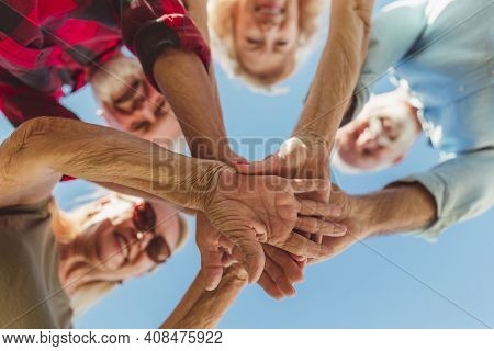 Low Angle View Of Group Of Cheerful Active Senior People Enjoying Sunny Summer Day Outdoors, Gathere