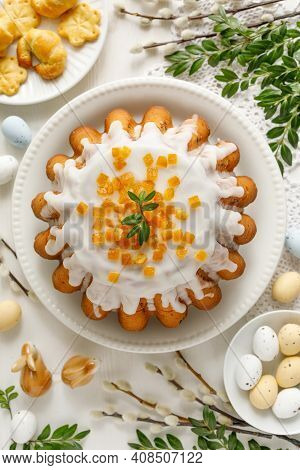 Easter Yeast Cake Babka Covered With Icing With Candied Orange Peel On A White Plate Top View. A Tra