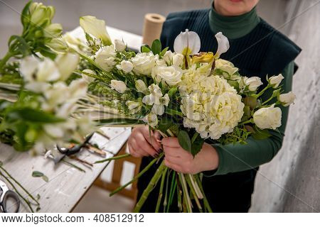 Florist Workplace On The Light Background. The Florist Creates A Floral Arrangement Of Roses, Lilacs