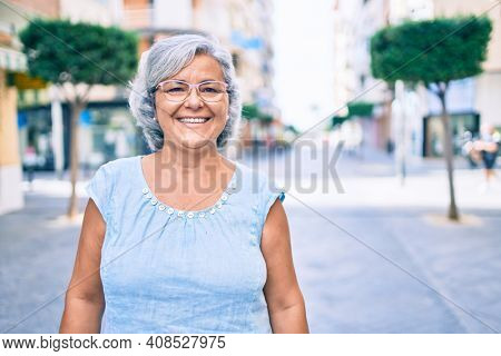 Middle age woman with grey hair smiling happy outdoors