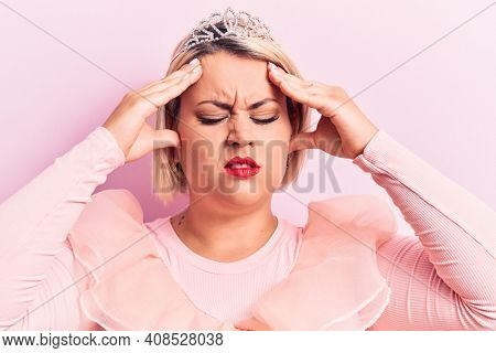 Beautiful blonde plus size woman wearing pincess tiara with diamonds over pink background with hand on head, headache because stress. Suffering migraine.