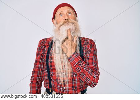 Old senior man with grey hair and long beard wearing hipster look with wool cap thinking concentrated about doubt with finger on chin and looking up wondering 