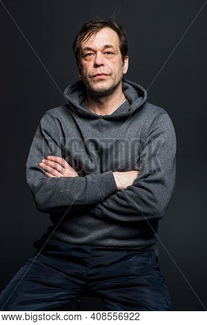 Studio Portrait Of A 40-50-year-old Serious Man In A Gray Hoodie On A Neutral Background, Looking Di
