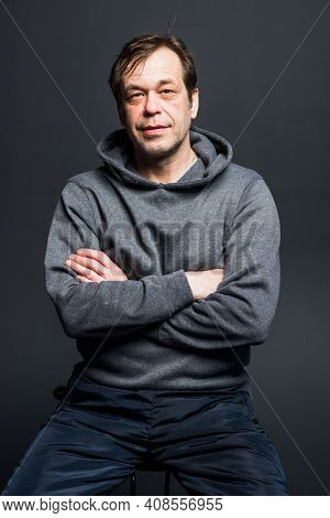 Studio Portrait Of A 40-50-year-old Smiling Man In A Gray Hoodie On A Neutral Background, Looking Di