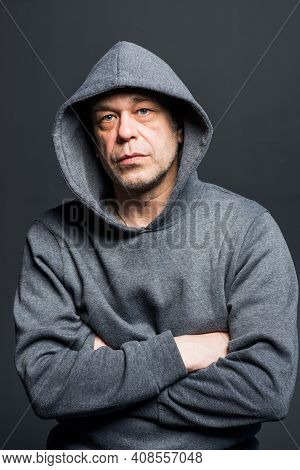 Studio Portrait Of A 40-50-year-old Serious Man In A Gray Hoodie On A Neutral Background, Eyes Direc