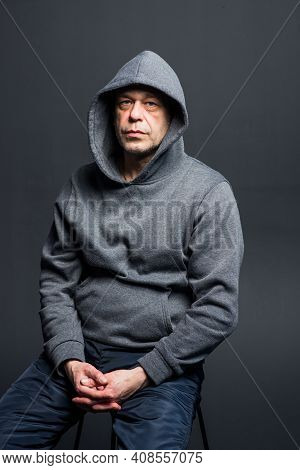 Studio Portrait Of A 40-50-year-old Serious Man In A Gray Hoodie On A Neutral Background, Eyes Direc