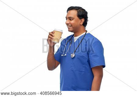 healthcare, profession and medicine concept - happy smiling indian doctor or male nurse in blue uniform with takeaway coffee cup and stethoscope over white background