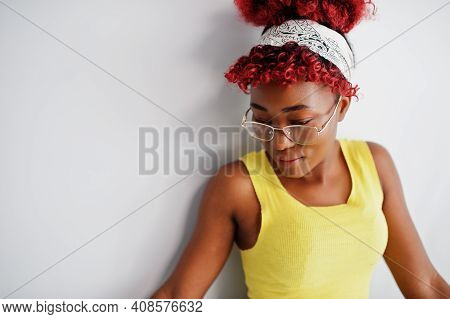 African American Woman In Yellow Singlet And Eyglasses Against White Wall.