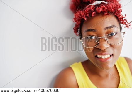 African American Woman In Yellow Singlet And Eyglasses Against White Wall.