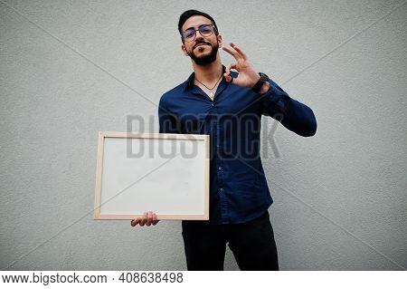 Middle Eastern Man Wear Blue Shirt, Eyeglasses, Hold White Empty Board.