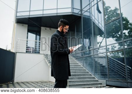 Middle Eastern Man Wear Black Coat, Eyeglasses, Writing Contract On Clipboard.