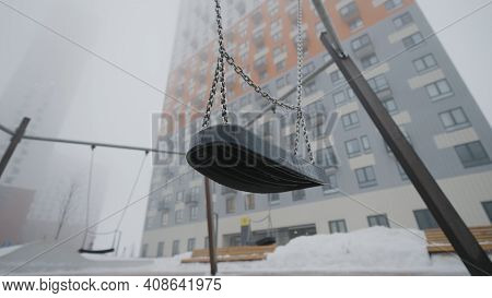 Swing On Background Of Houses In Fog. Action. Empty Swing Eerily Seesaw On Background Of Fog. Empty 