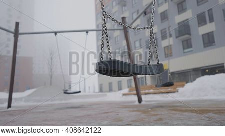 Swing On Background Of Houses In Fog. Action. Empty Swing Eerily Seesaw On Background Of Fog. Empty 