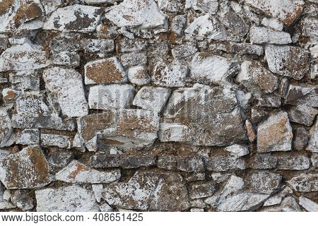 Old Stone Wall, Painted In A Faded White Color And Built With Stones And Mud
