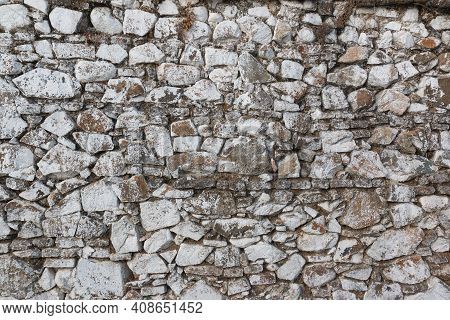 Old Stone Wall, Painted In A Faded White Color And Built With Stones And Mud
