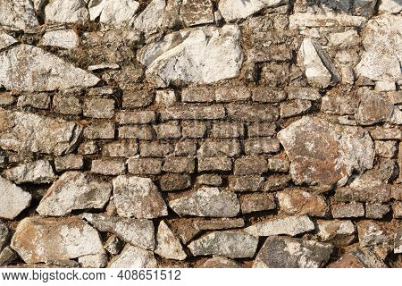 Old Stone Wall, Painted In A Faded White Color And Built With Stones And Mud