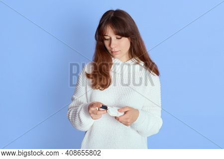 Woman Holding Electronic Cigarette, Looking Down At Device, Female Wearing White Jumper, Smoking E C