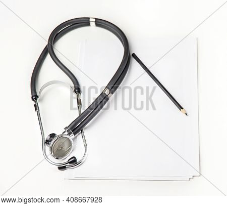 Stethoscope On A White Background And White Paper Whith Pencil On The Table