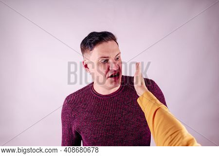 Crop Person Slapping Scared Man In Face. Emotional Male Getting Slapped In Face While Shouting With