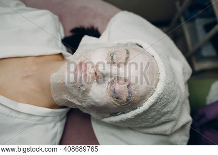 Paraffin Face Mask Gauze Bandage Therapy Young Woman Receiving Facial Skin Care Treatment. Beauticia