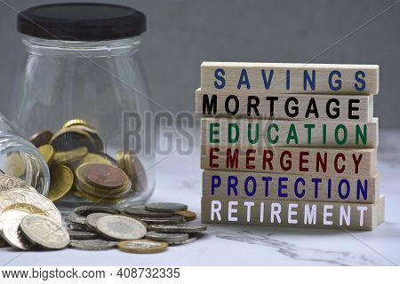 Text On Wood Block And Glass Jars With Multicurrency Coins - Savings, Mortgage, Educations, Emergenc