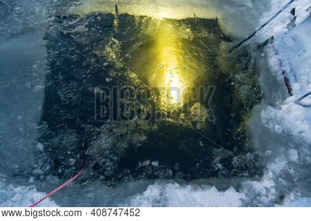A Diver From Under The Water Shines With A Flashlight Torch An Ice Hole Entry With A For Ice Scuba D