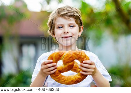 Adorable Little Kid Boy Eating Huge Big Bavarian German Pretzel. Happy Blond Child Enjoying Tasteful