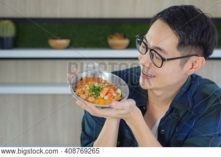 Young Man Wearing Glasses Holding The Fried Egg Served On A Pan With Colorful Toppings Served On A P